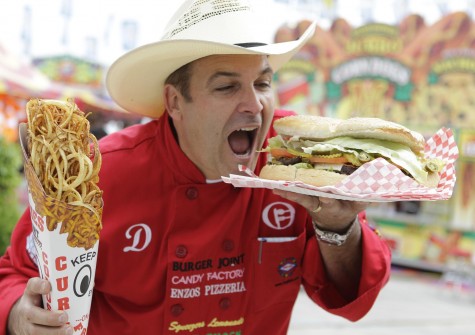 Dominic Palmieri of Phoenix with RSC Carnivals poses with the 17 inch cone of Colossal Curly Fries and the 4 pound Belly Buster Burger during the Golden Buckle Foodie Awards competition at the Houston Livestock Show and Rodeo Thursday, March 1, 2012, in Houston.  ( Melissa Phillip / Houston Chronicle )